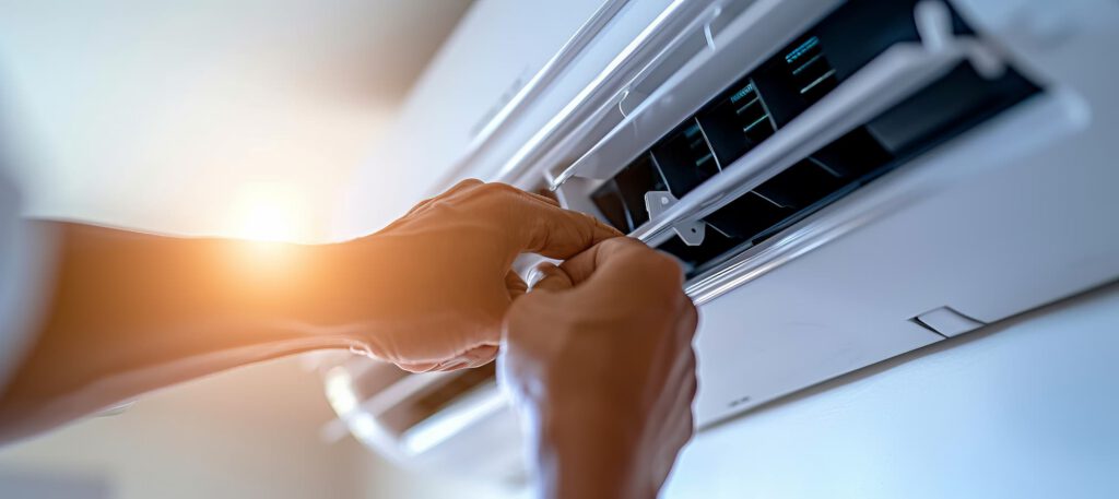Technician adjusting the airflow louvers on a wall-mounted split air conditioning unit during servicing.