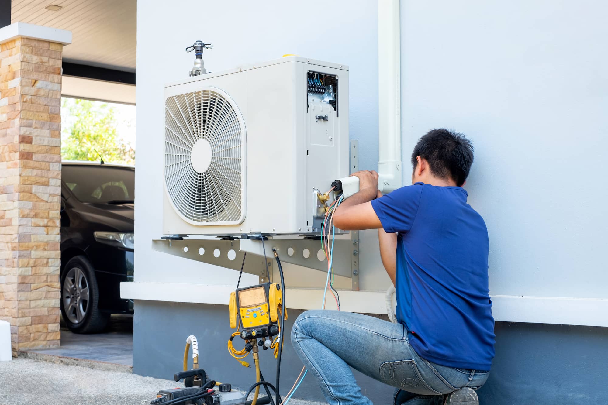 Technician carrying out maintenance on an outdoor air conditioning condenser unit.